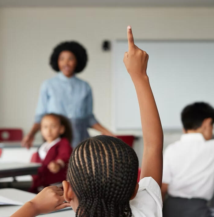 Choices in the classroom Image of a student with a raised hand with a teacher in the background.